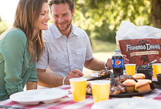 man and woman eating Famous Dave's BBQ at a picnic